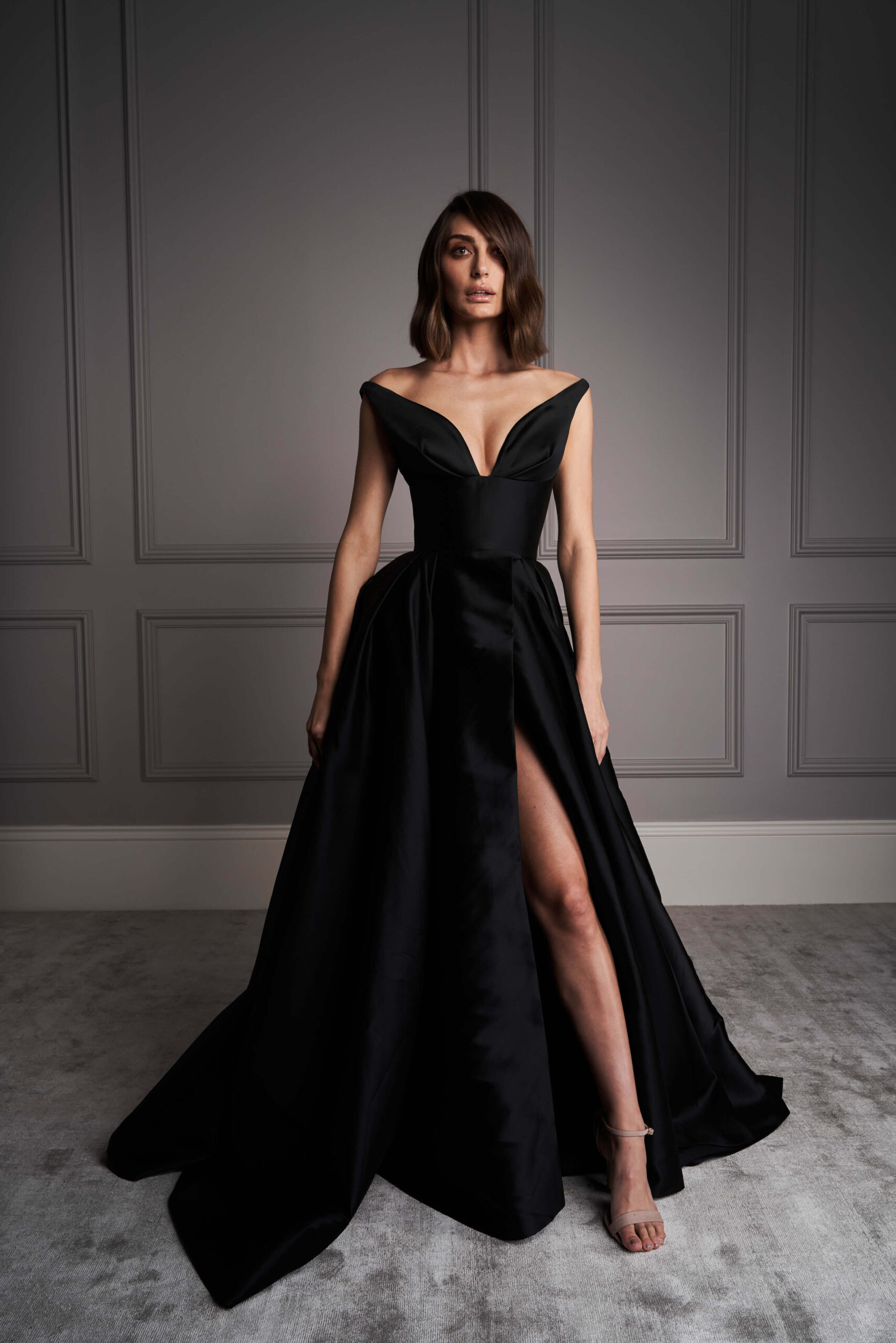 Darling off shoulder sleeves ornament this black bridal gown. a asymmetric slit compliments the gown structure